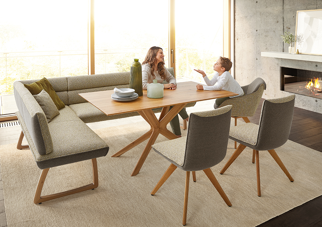 Esszimmergruppe mit Eckbank, Stühlen und Esstisch aus Massivholz im Koinor-Dining-System von Polstermöbel Fischer – modernes Ambiente mit Kamin.