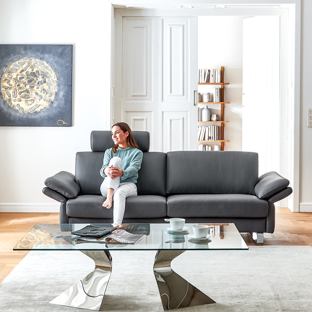Frau sitzt auf der Couch in modernem Wohnzimmer.