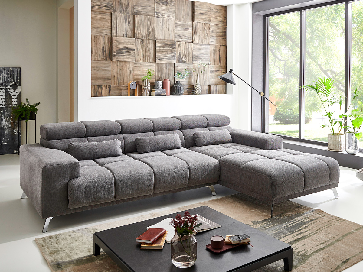 Geräumiges Wohnzimmer mit grauem Ecksofa und hölzerner Wandgestaltung.