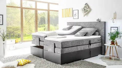 Gemütliches Schlafzimmer mit großen Fenstern und Boxspringbett.