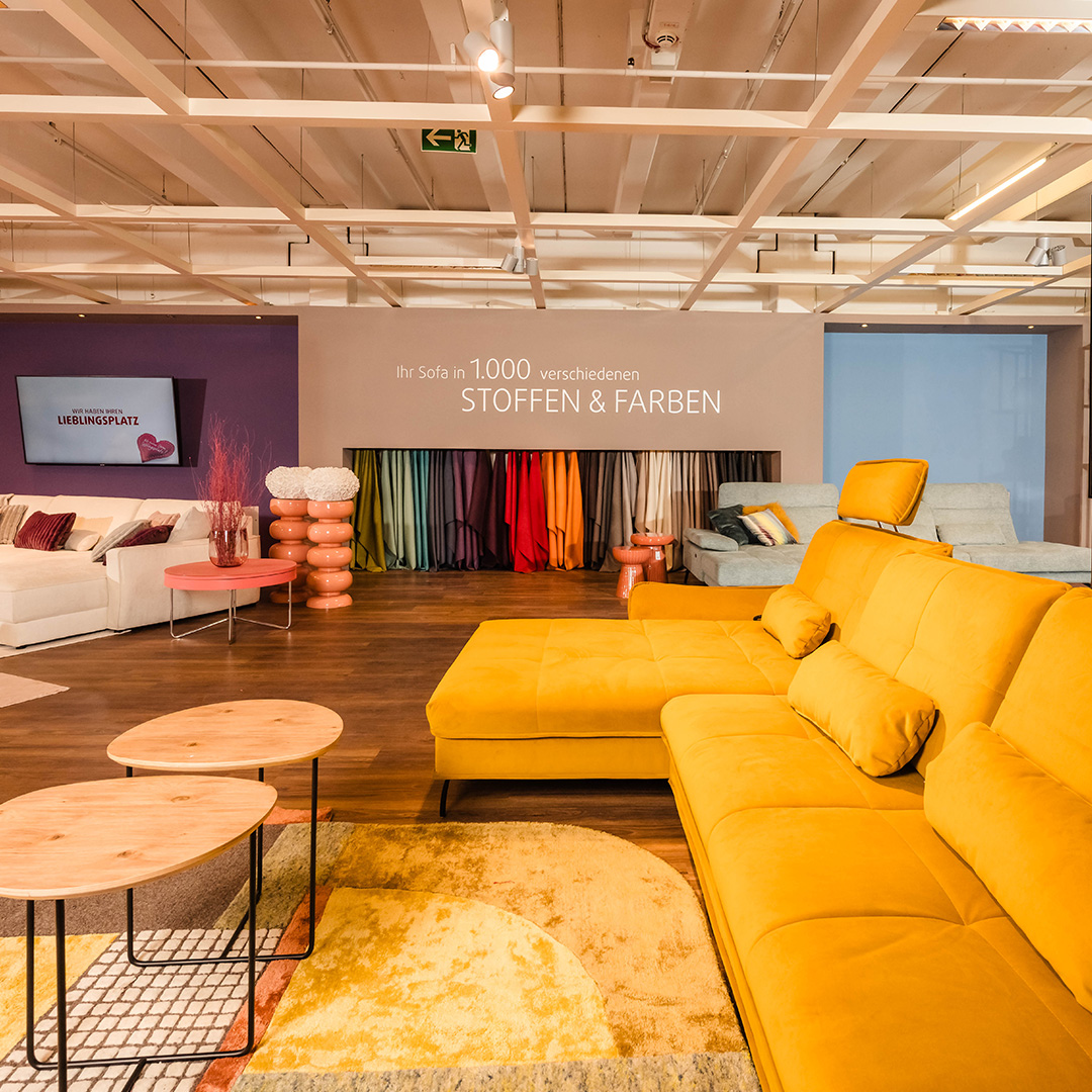 Sofa-Ausstellung bei Polstermöbel Fischer Nürnberg mit gelber Wohnlandschaft, Couchtischen und großer Stoff- und Farbauswahl.