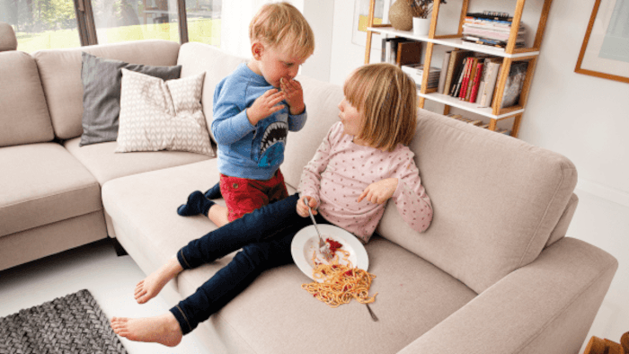 Kinder essen Nudel auf der Couch