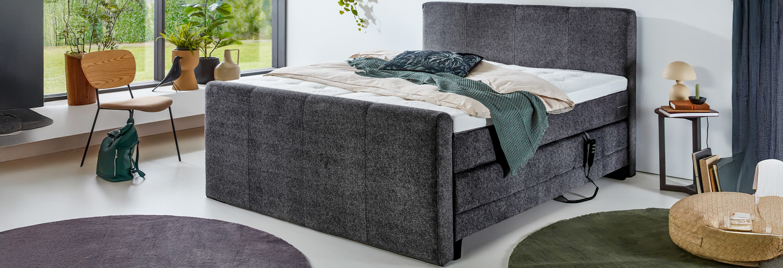 Modernes Boxspringbett in grauem Stoffbezug mit hohem Kopf- und Fußteil, elektrisch verstellbarer Unterbox und stilvoller Schlafzimmerdekoration
