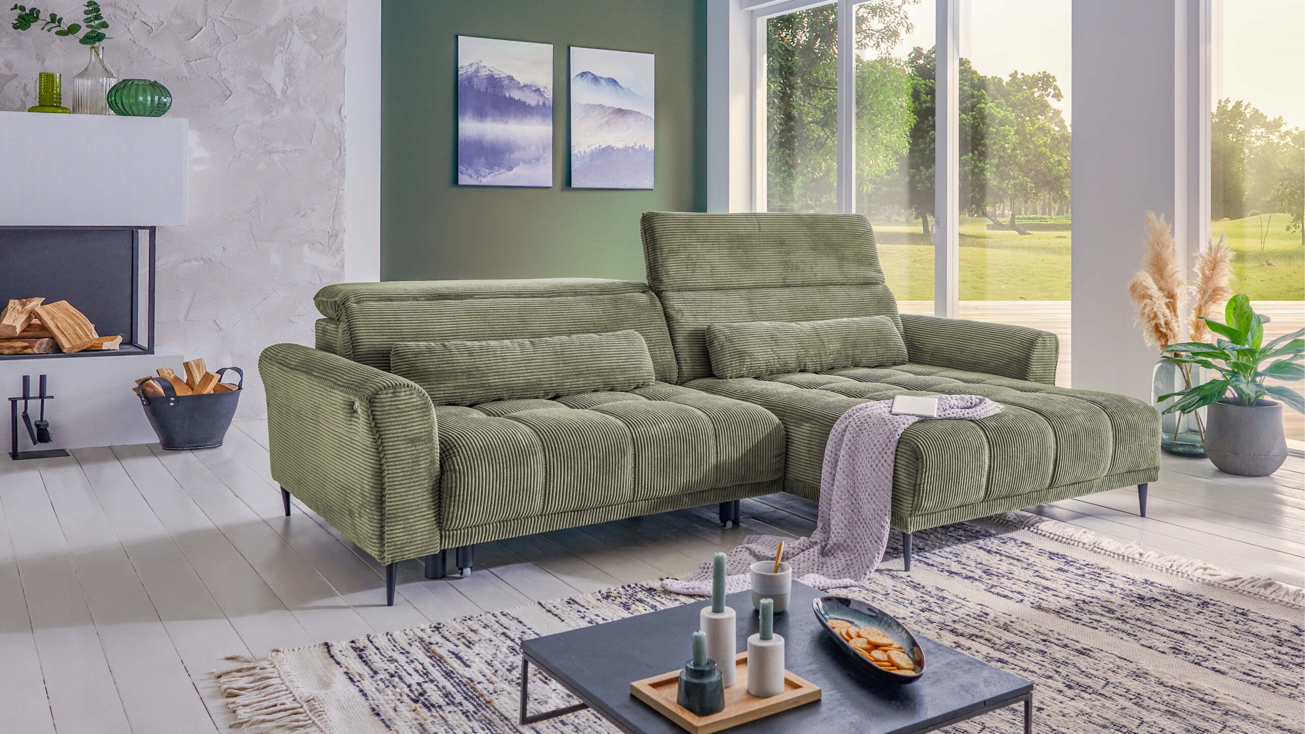 Grünes Cord-Ecksofa mit Schlaffunktion in modernem Wohnzimmer – gemütliche Sitzecke mit verstellbaren Rückenlehnen, Dekokissen und stilvollem Ambiente.