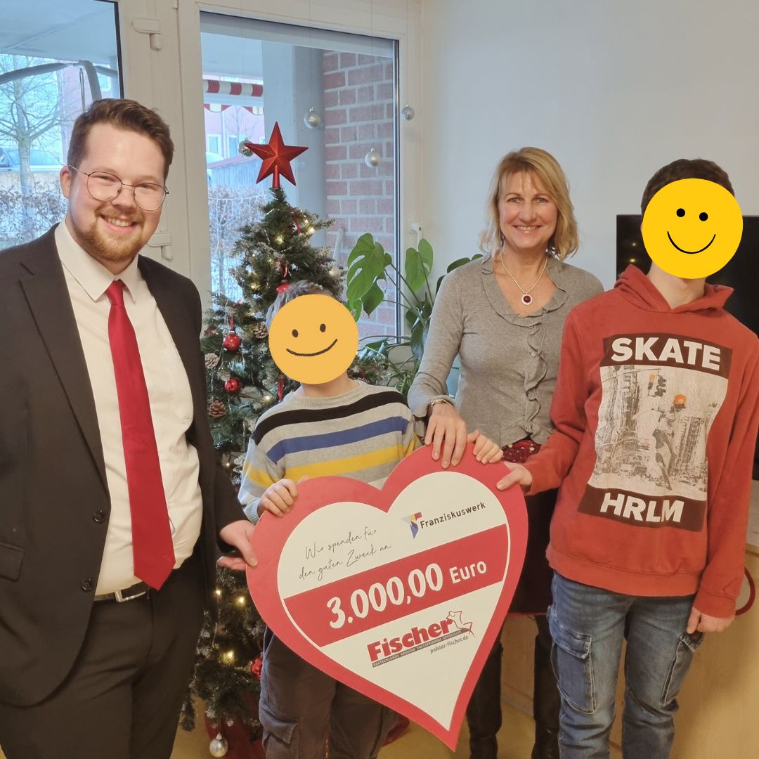 Mitarbeitende von Polstermöbel Fischer überreichen im Dezember eine Spende über 3.000 Euro an das Franziskuswerk, weihnachtliche Atmosphäre mit Tannenbaum