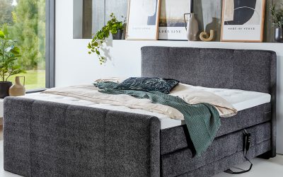 Modernes Boxspringbett in grauem Stoffbezug mit hohem Kopf- und Fußteil, elektrisch verstellbarer Unterbox und stilvoller Schlafzimmerdekoration